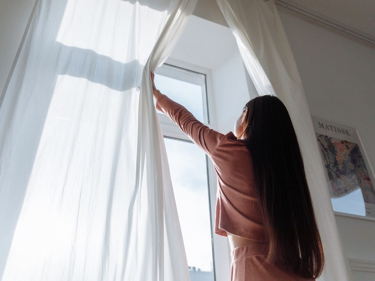 White curtains being hung in a bright room
