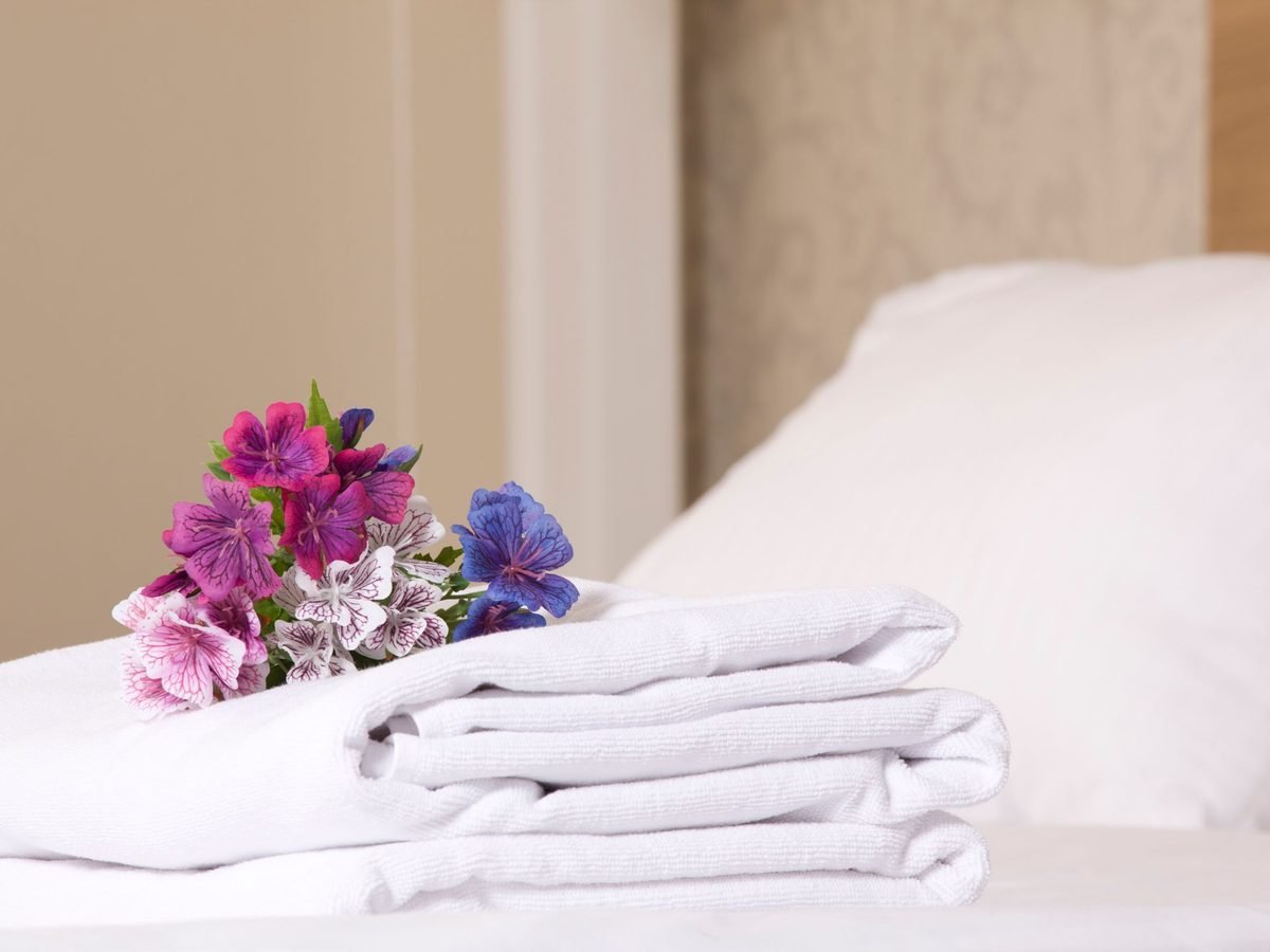 Fresh white towels folded on a made bed